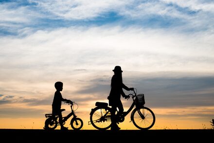 Mutter und Kind beim Radfahren im Sonnenuntergang